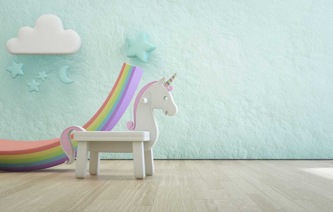 White toy unicorn on wooden floor of kids room with empty rough blue concrete texture wall background.